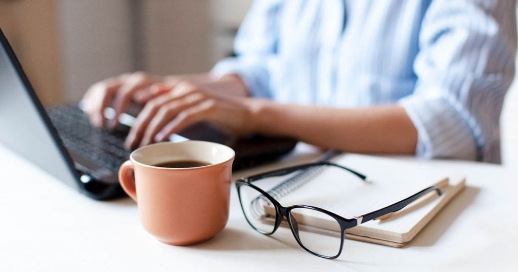 Télétravail sécurisé pour PME normandes – salarié travaillant à domicile sur ordinateur portable avec café et carnet